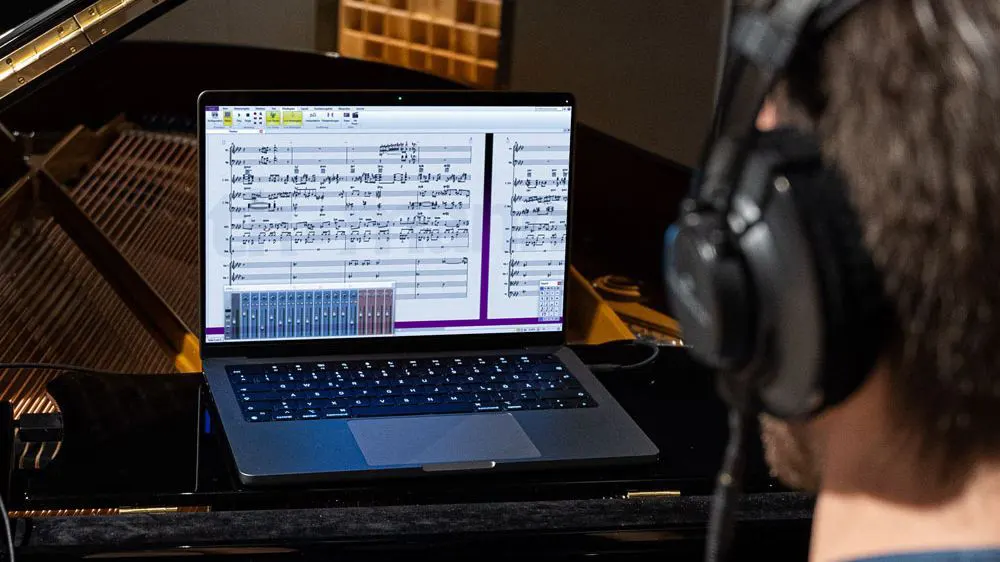 C. Bechstein Piano Connect System - Notation / Writing Down Music - Person at Bechstein piano with headphones and laptop with sheet music on screen
